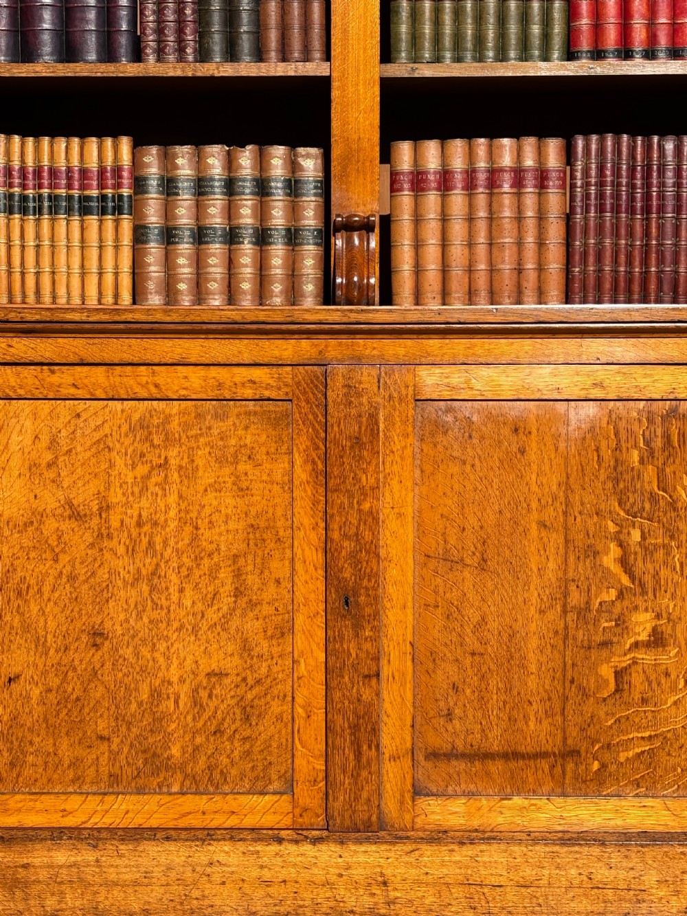 A two-section 19th-century oak open bookcase featuring carved corbels flanking the upper shelves and a double-panelled cupboard base. View III