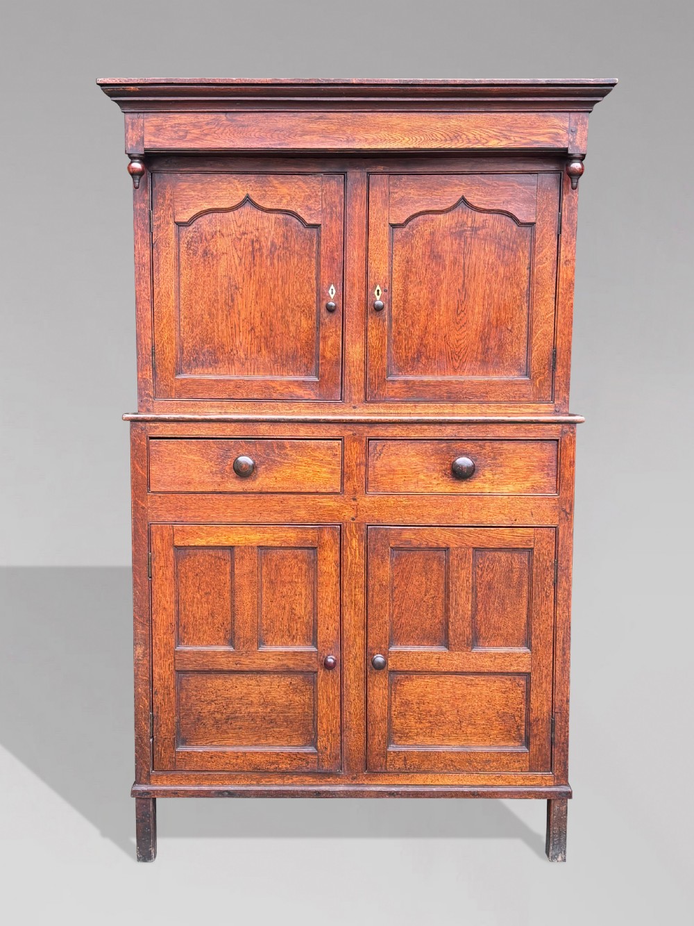 An eighteenth-century George III oak court cupboard featuring an overhanging canopy with turned pendants, upper panelled doors, two drawers, and a double-door base. View II