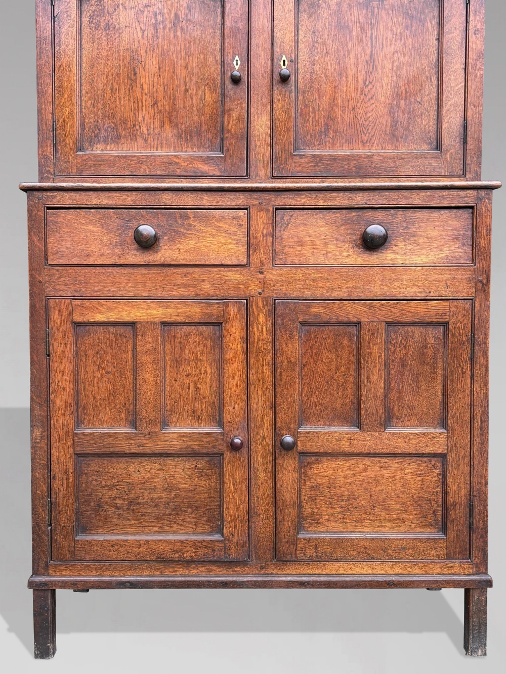 An eighteenth-century George III oak court cupboard featuring an overhanging canopy with turned pendants, upper panelled doors, two drawers, and a double-door base. View III