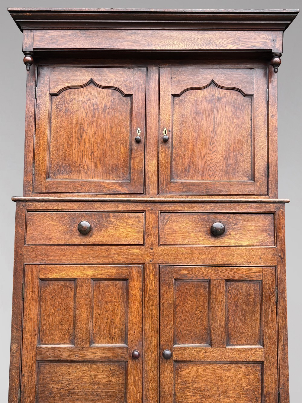An eighteenth-century George III oak court cupboard featuring an overhanging canopy with turned pendants, upper panelled doors, two drawers, and a double-door base. View IV