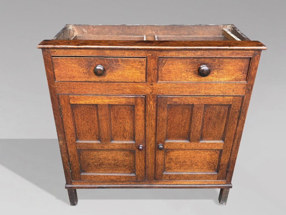 An eighteenth-century George III oak court cupboard featuring an overhanging canopy with turned pendants, upper panelled doors, two drawers, and a double-door base. View V