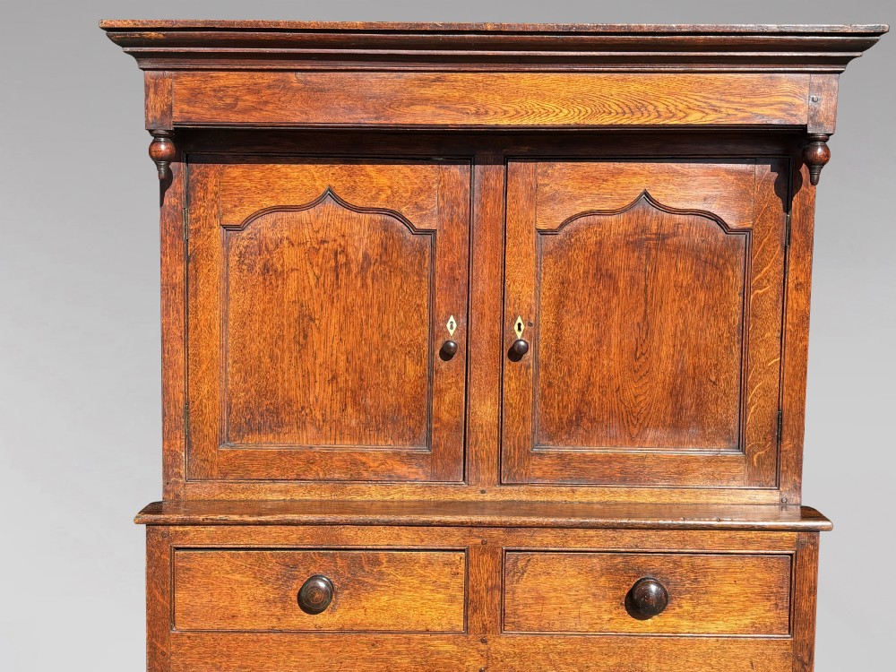 An eighteenth-century George III oak court cupboard featuring an overhanging canopy with turned pendants, upper panelled doors, two drawers, and a double-door base. View VI