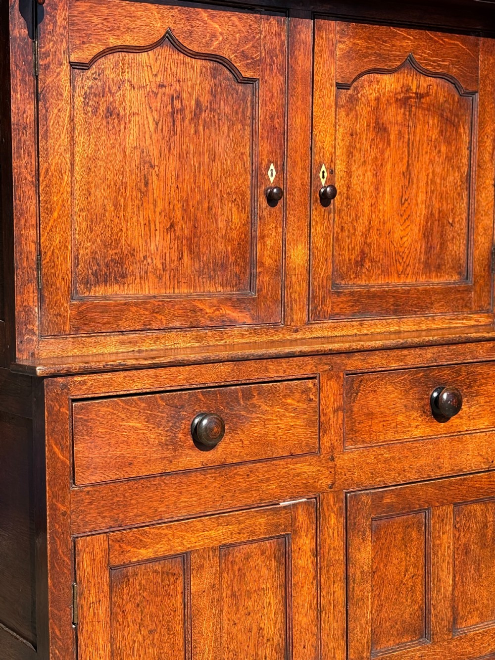 An eighteenth-century George III oak court cupboard featuring an overhanging canopy with turned pendants, upper panelled doors, two drawers, and a double-door base. View VII