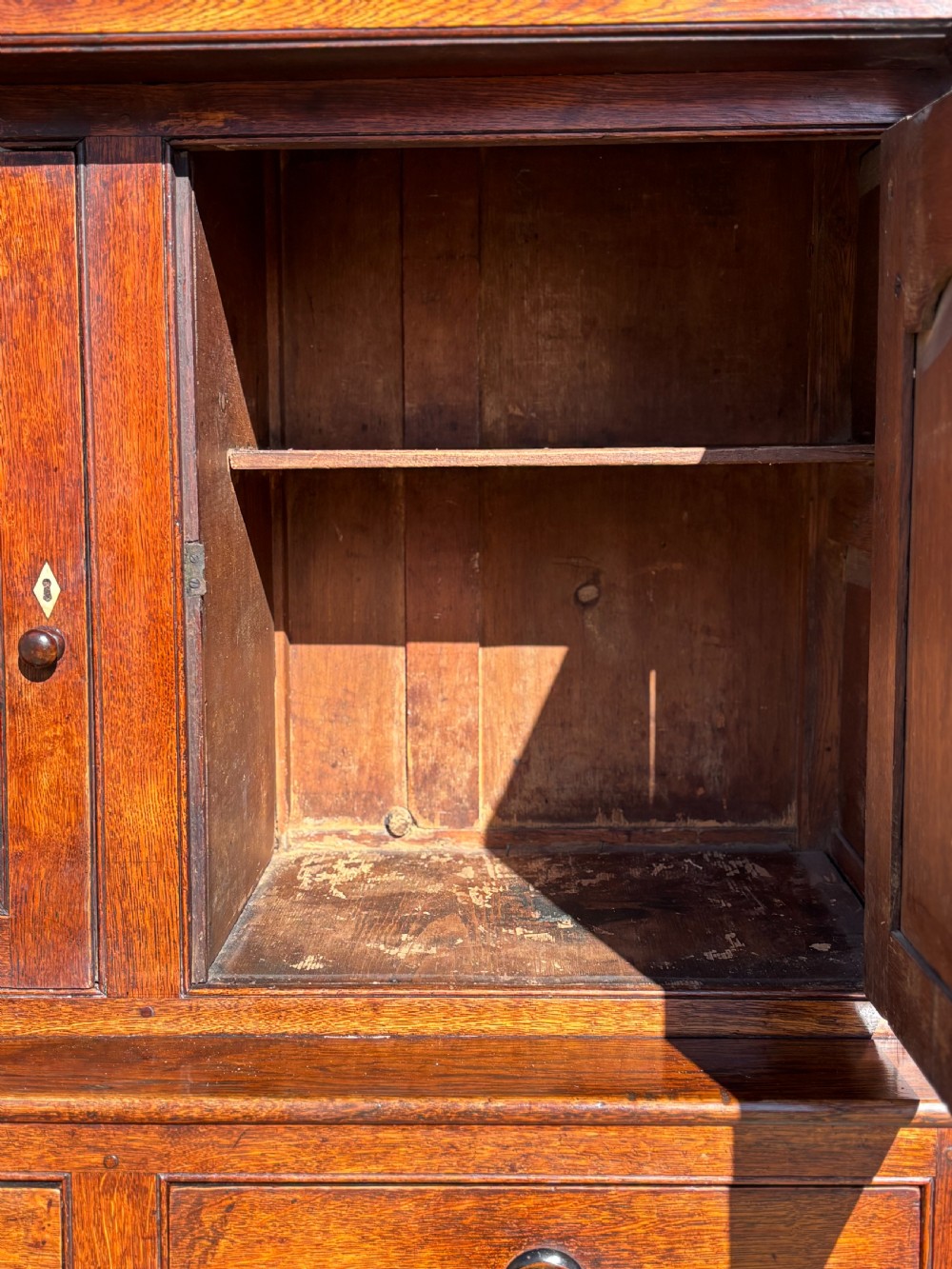 An eighteenth-century George III oak court cupboard featuring an overhanging canopy with turned pendants, upper panelled doors, two drawers, and a double-door base. View VIII
