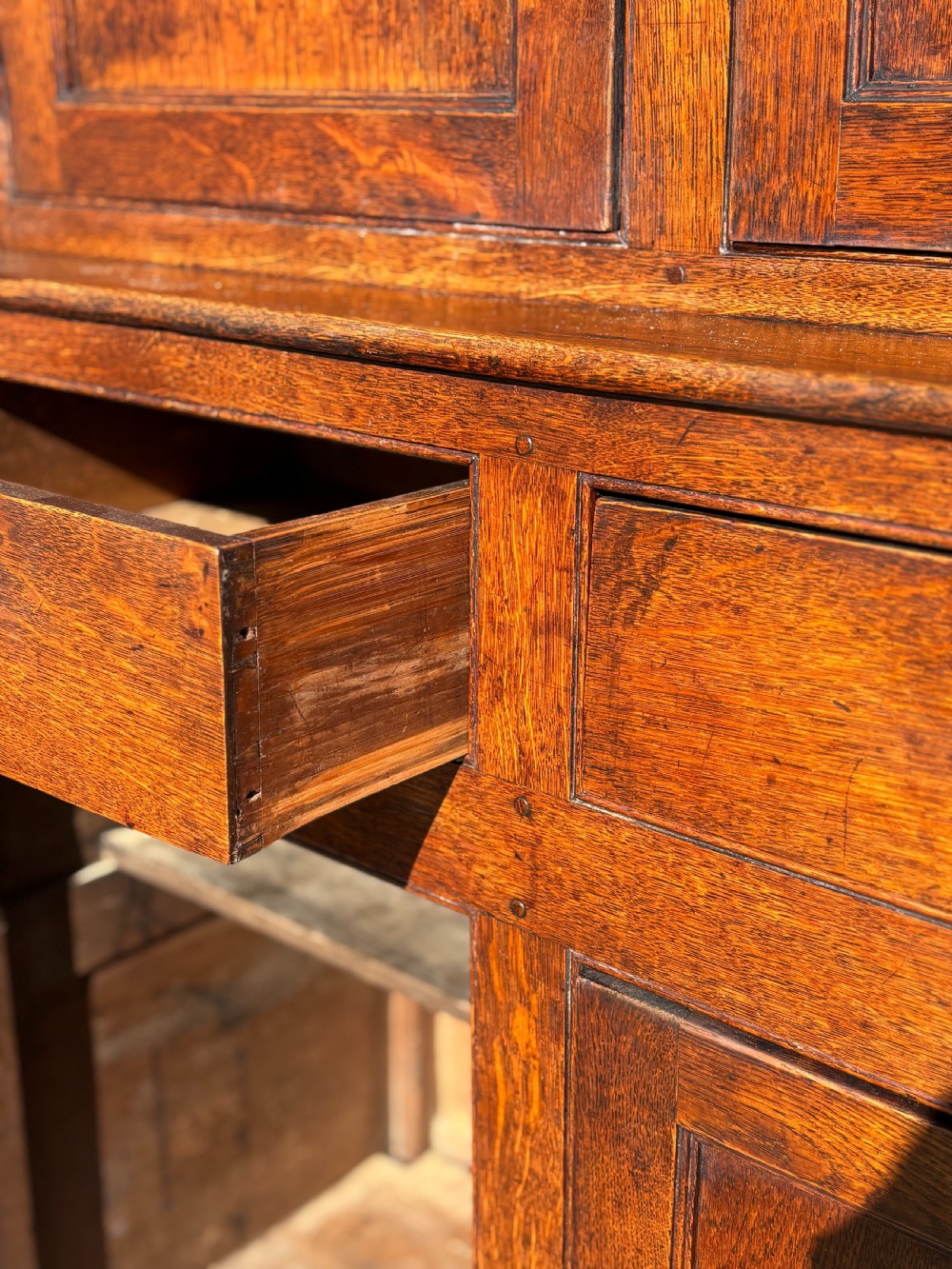 An eighteenth-century George III oak court cupboard featuring an overhanging canopy with turned pendants, upper panelled doors, two drawers, and a double-door base. View IX