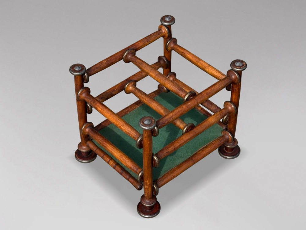 A late nineteenth-century walnut magazine rack with turned spindle framing, metal accents, central dividers, and a green fabric base. View V