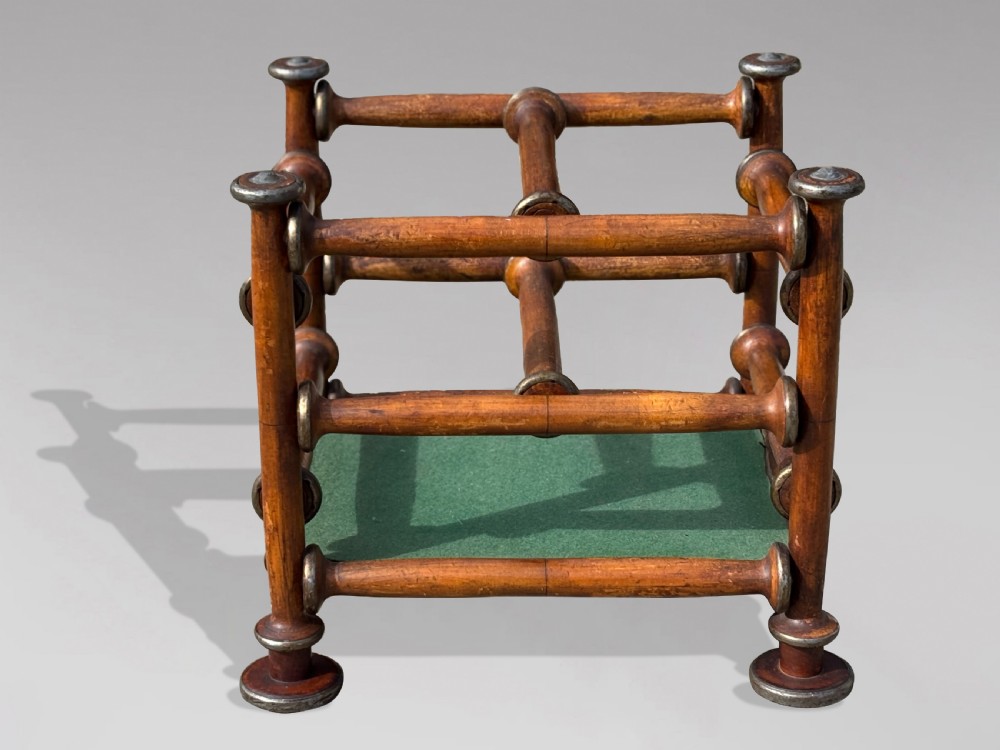 A late nineteenth-century walnut magazine rack with turned spindle framing, metal accents, central dividers, and a green fabric base. View VI