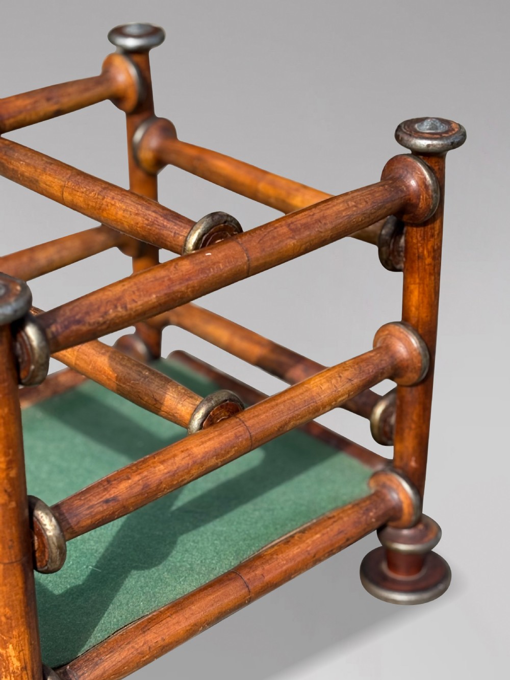 A late nineteenth-century walnut magazine rack with turned spindle framing, metal accents, central dividers, and a green fabric base. View VII