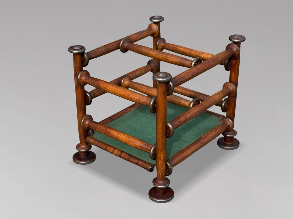 A late nineteenth-century walnut magazine rack with turned spindle framing, metal accents, central dividers, and a green fabric base. View VIII