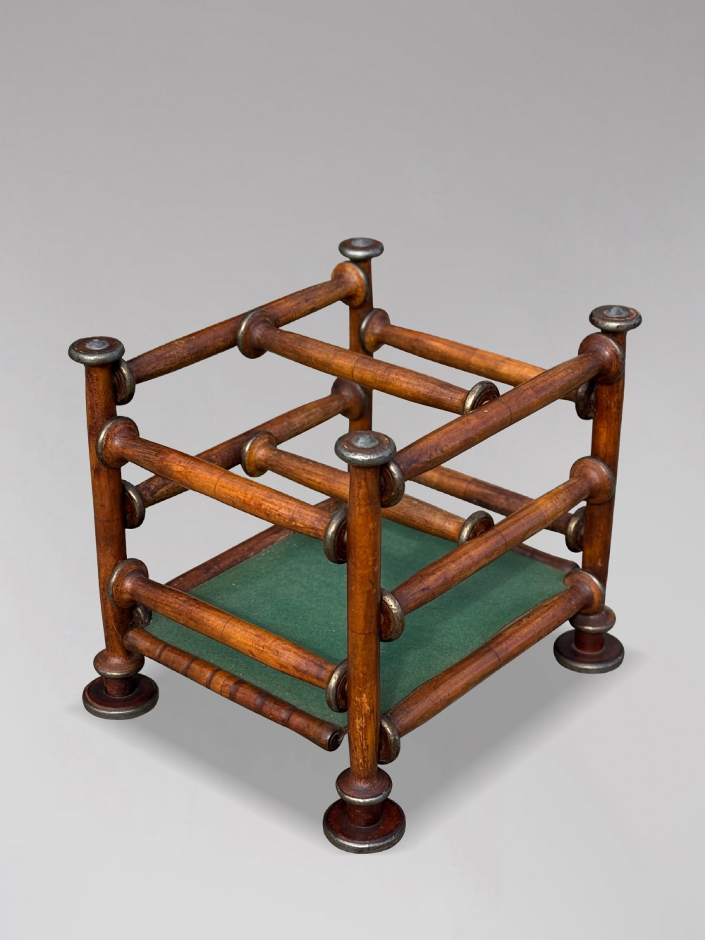 A late nineteenth-century walnut magazine rack with turned spindle framing, metal accents, central dividers, and a green fabric base. View IX