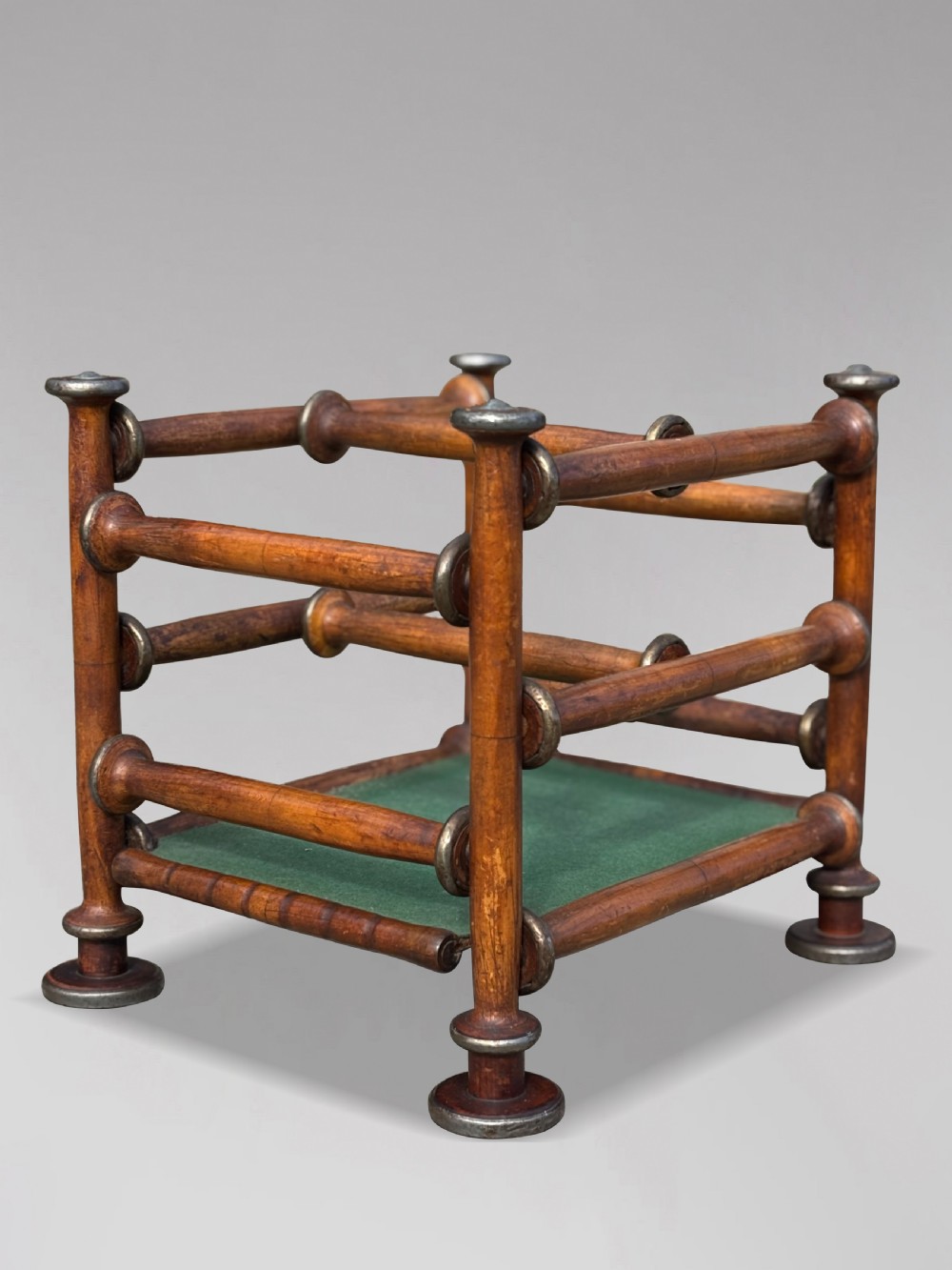 A late nineteenth-century walnut magazine rack with turned spindle framing, metal accents, central dividers, and a green fabric base. View X
