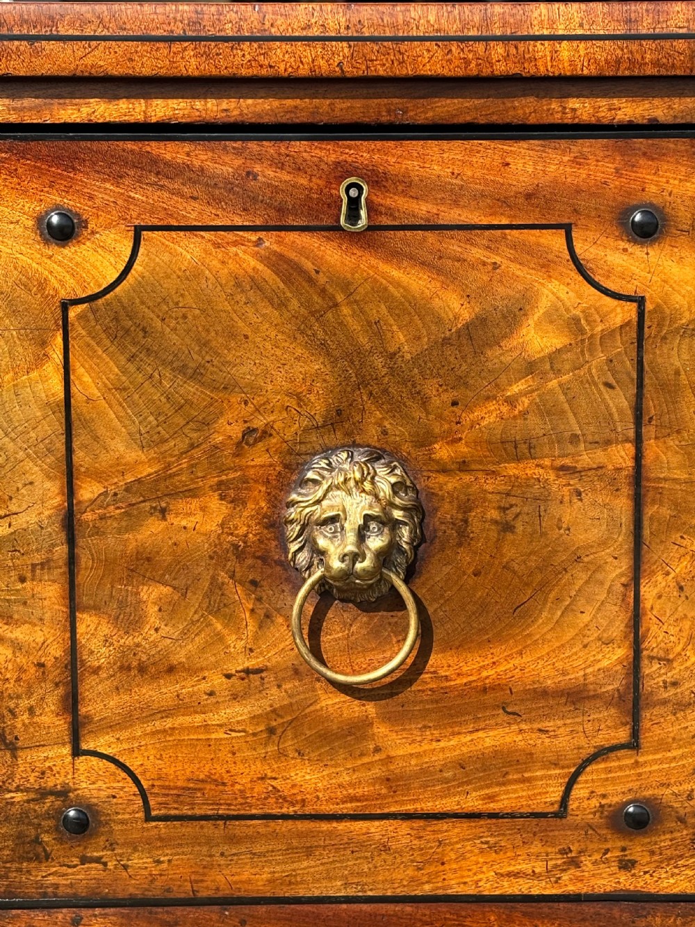 A 19th-century George IV flame mahogany breakfront sideboard featuring ebony stringing, lion-mask brass handles, spiral pilasters, and fluted legs. View III