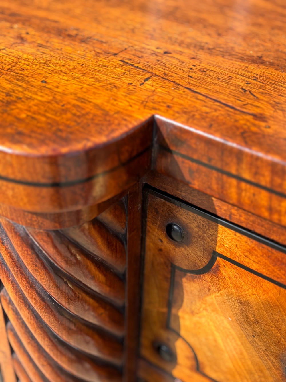 A 19th-century George IV flame mahogany breakfront sideboard featuring ebony stringing, lion-mask brass handles, spiral pilasters, and fluted legs. View IX