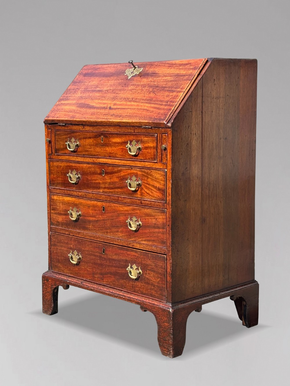 An 18th-century George III mahogany bureau featuring an open sloping slant front revealing small drawers and pigeonholes above four long drawers on bracket feet. View III