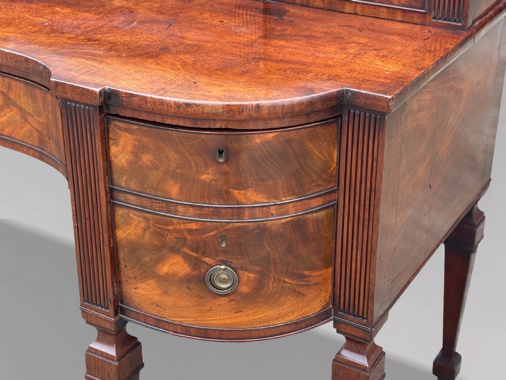 An 18th-century George III flame mahogany sideboard featuring a raised stage back, oval wood inlays, fluted side columns, and six turned reeded legs. View V