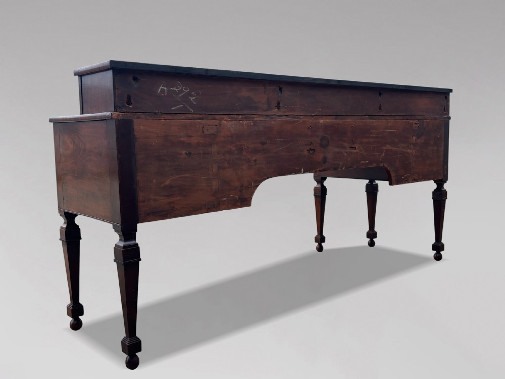An 18th-century George III flame mahogany sideboard featuring a raised stage back, oval wood inlays, fluted side columns, and six turned reeded legs. View VII