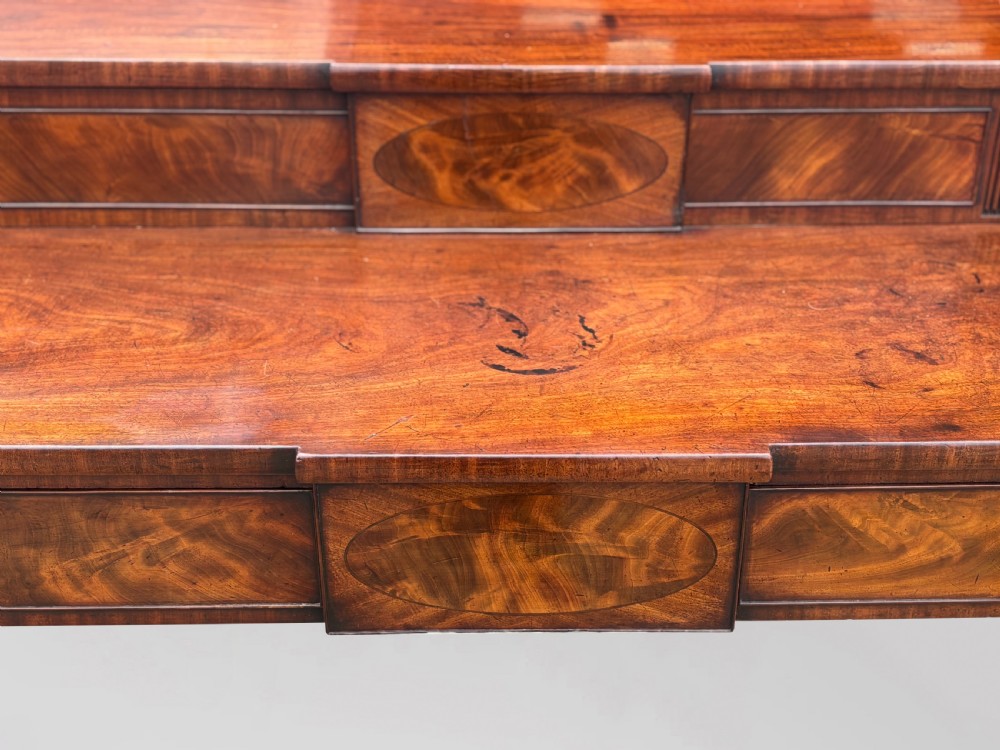 An 18th-century George III flame mahogany sideboard featuring a raised stage back, oval wood inlays, fluted side columns, and six turned reeded legs. View IX