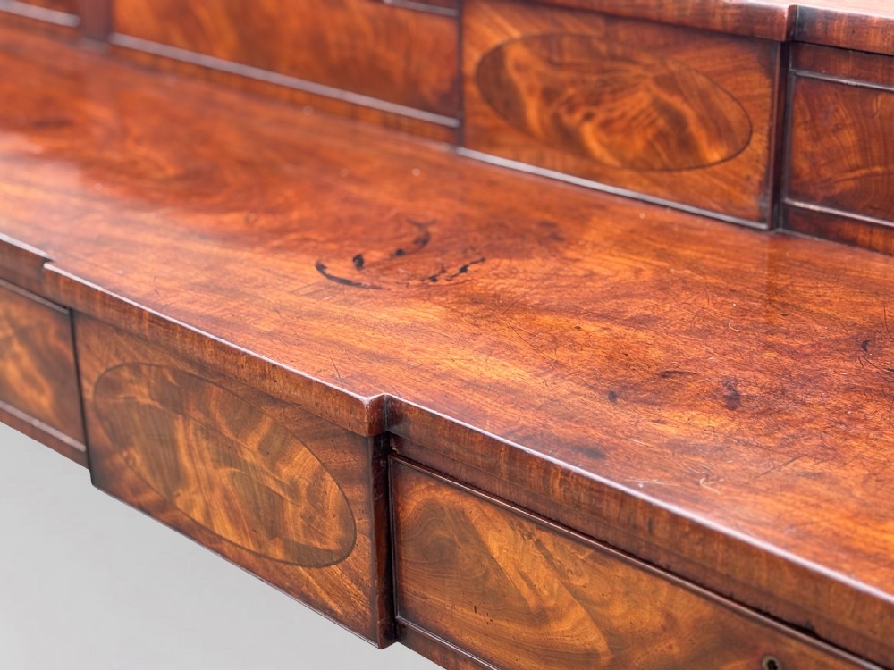 An 18th-century George III flame mahogany sideboard featuring a raised stage back, oval wood inlays, fluted side columns, and six turned reeded legs. View XIII