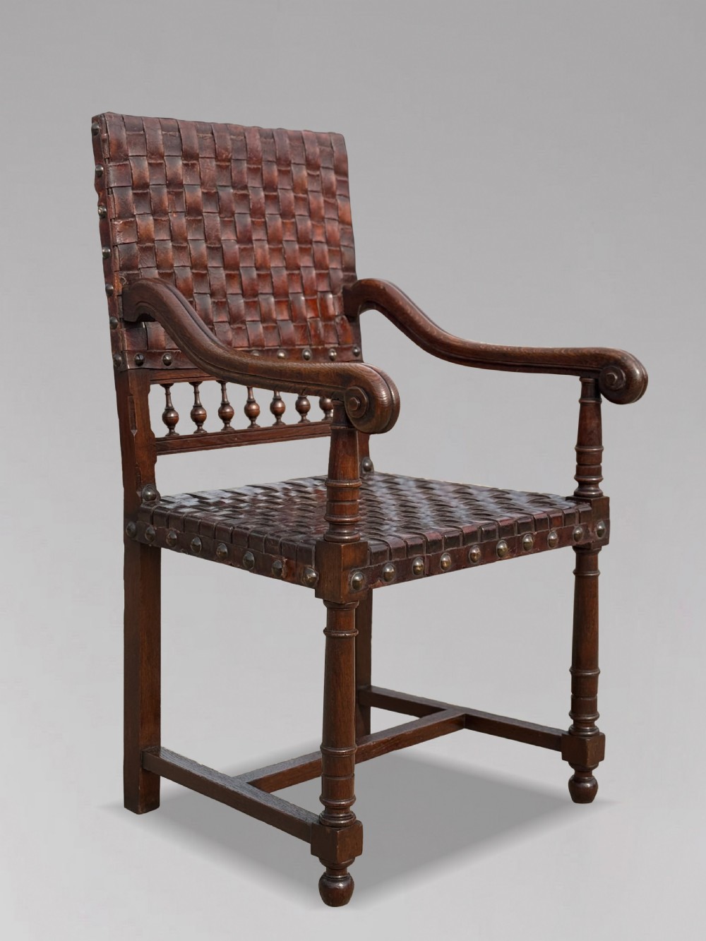 A pair of late 19th-century dark oak armchairs featuring woven brown leather backrests and seats with brass stud detailing and turned legs. View IX