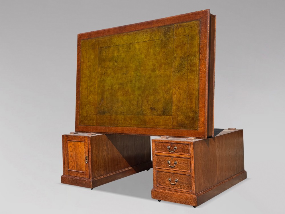 A late 19th-century oak partners desk featuring a green leather inset writing surface, twin pedestals with drawers and cupboards, and brass hardware. View III
