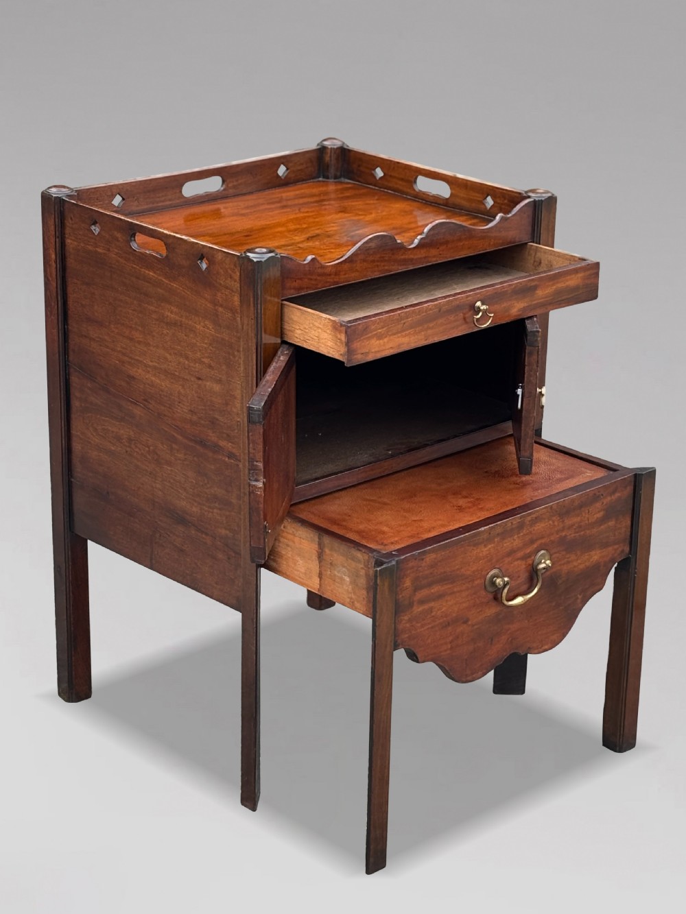 A pair of 18th-century George III mahogany bedside cabinets featuring tray tops with pierced handles, twin cupboard doors, and pull-out lower drawers with brass drop handles. View III
