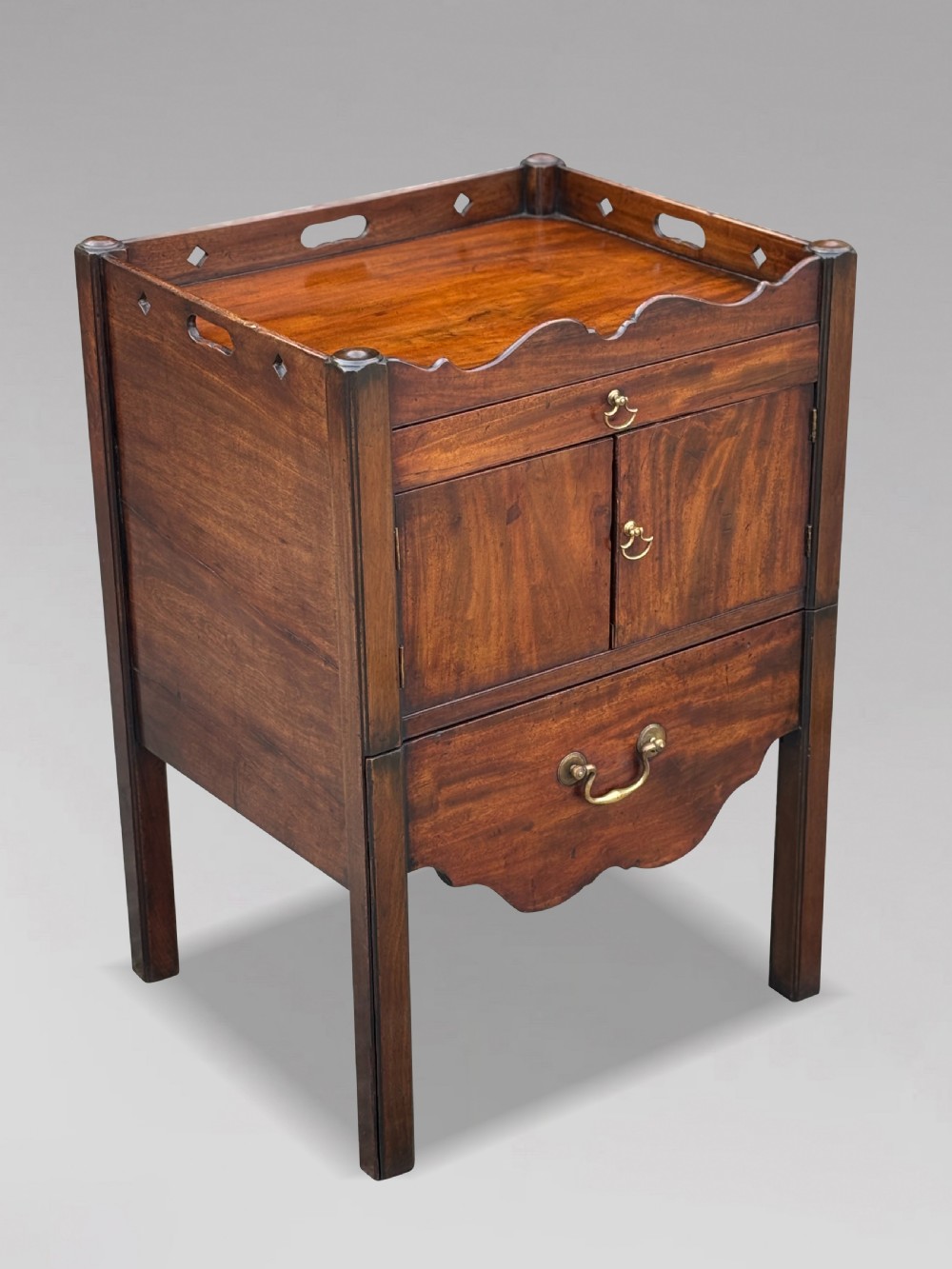 A pair of 18th-century George III mahogany bedside cabinets featuring tray tops with pierced handles, twin cupboard doors, and pull-out lower drawers with brass drop handles. View IV