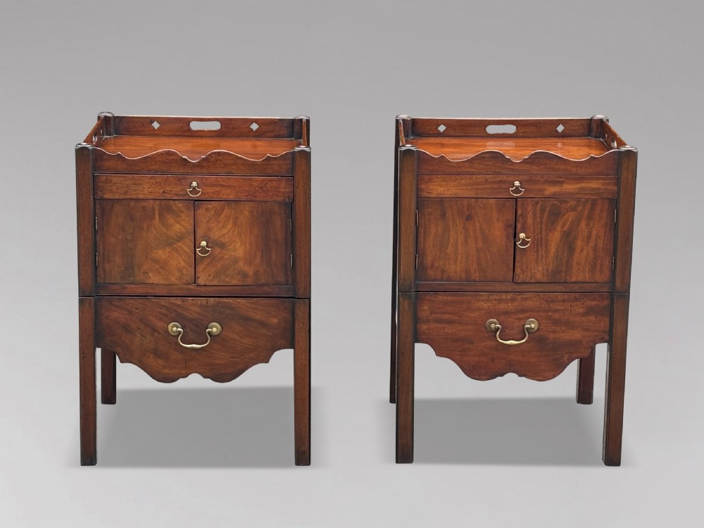 A pair of 18th-century George III mahogany bedside cabinets featuring tray tops with pierced handles, twin cupboard doors, and pull-out lower drawers with brass drop handles. View V