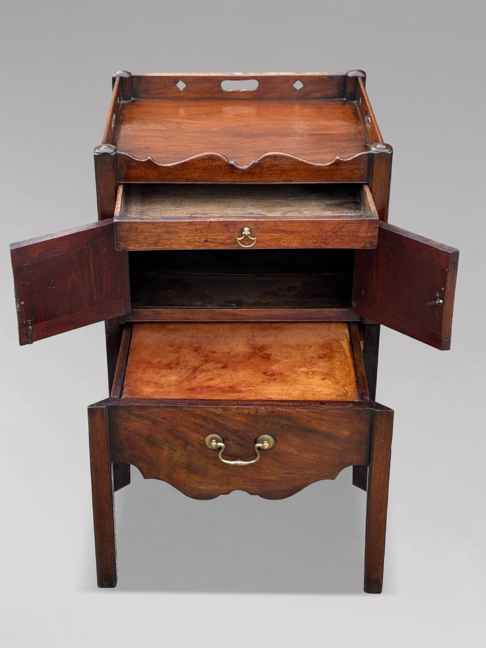 A pair of 18th-century George III mahogany bedside cabinets featuring tray tops with pierced handles, twin cupboard doors, and pull-out lower drawers with brass drop handles. View VI