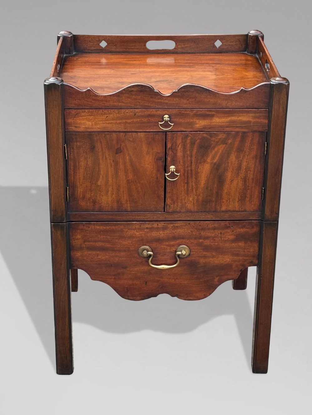 A pair of 18th-century George III mahogany bedside cabinets featuring tray tops with pierced handles, twin cupboard doors, and pull-out lower drawers with brass drop handles. View VII