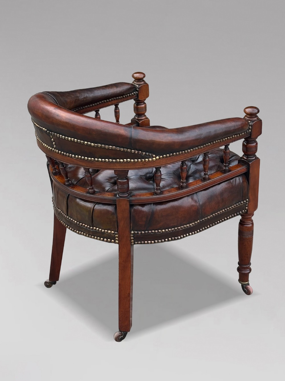 19th-century mahogany captains desk armchair upholstered in button-tufted brown leather with brass stud detail and turned spindles. View III