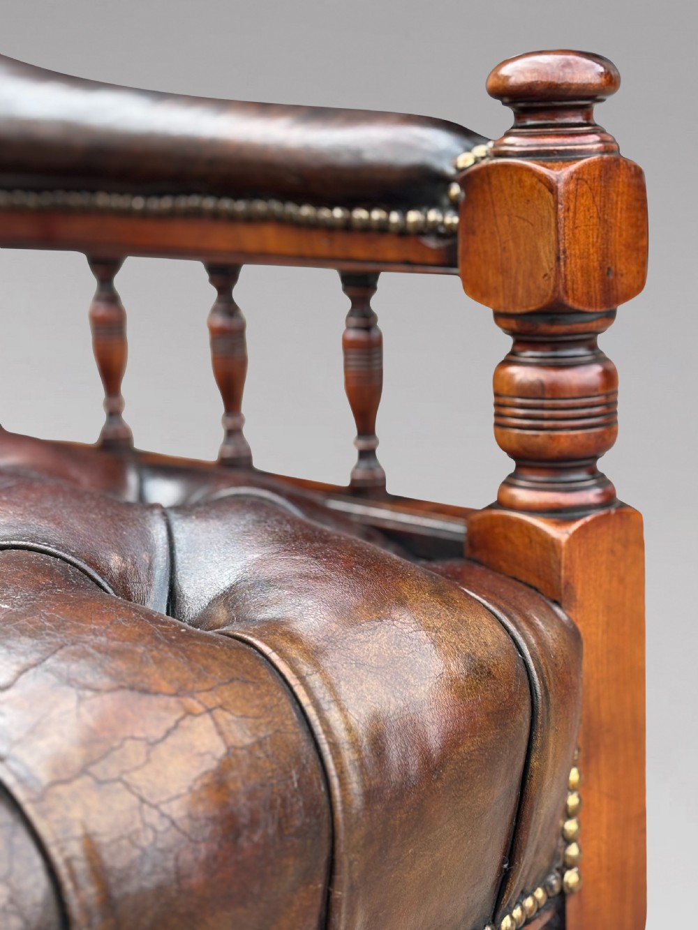 19th-century mahogany captains desk armchair upholstered in button-tufted brown leather with brass stud detail and turned spindles. View IV