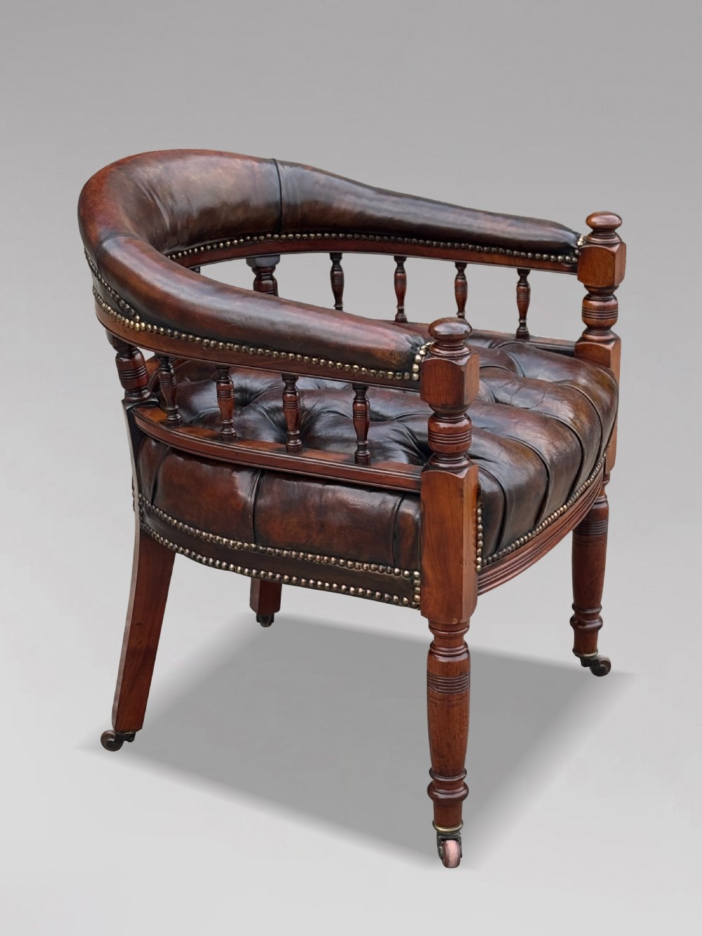 19th-century mahogany captains desk armchair upholstered in button-tufted brown leather with brass stud detail and turned spindles. View VII