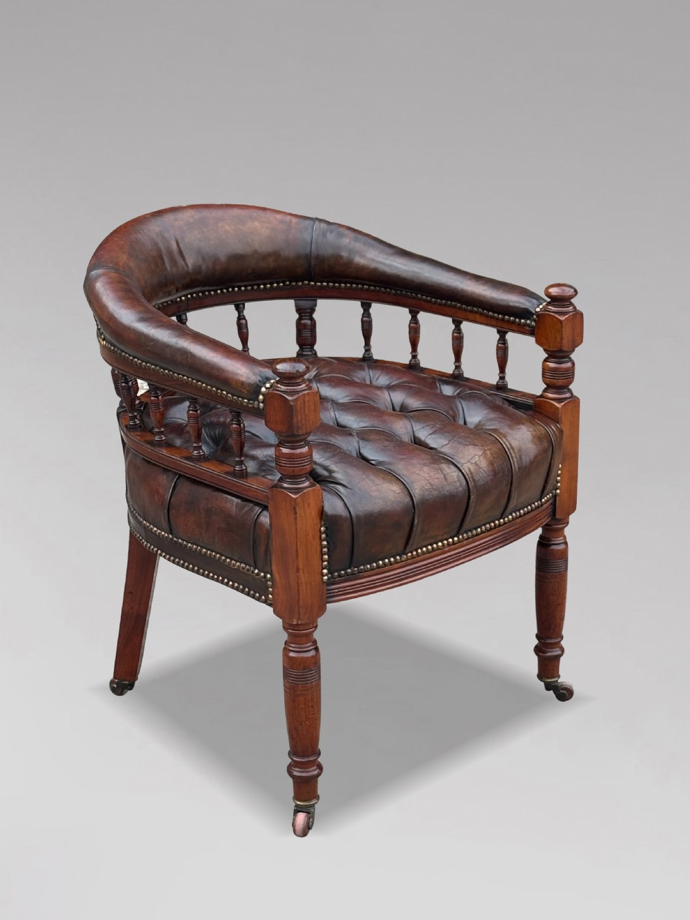 19th-century mahogany captains desk armchair upholstered in button-tufted brown leather with brass stud detail and turned spindles. View VIII