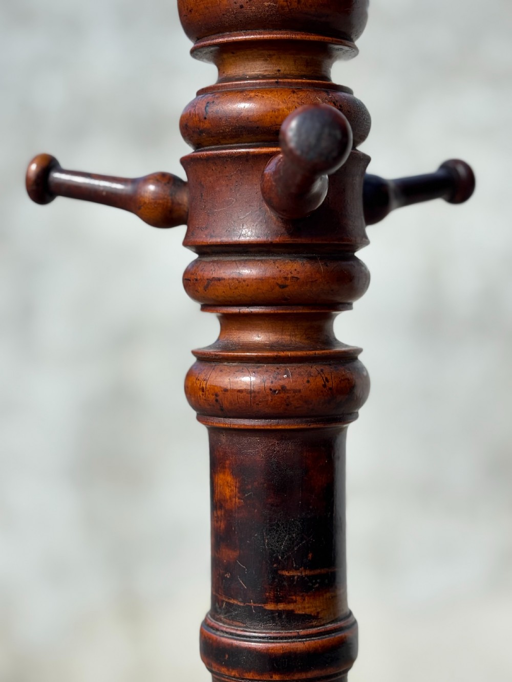 A dark brown bentwood hat and coat stand featuring upper scrolled hooks, a turned central column, a lower umbrella ring, and curved feet. View V