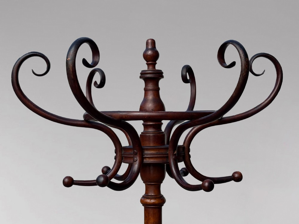 A dark brown bentwood hat and coat stand featuring upper scrolled hooks, a turned central column, a lower umbrella ring, and curved feet. View IX
