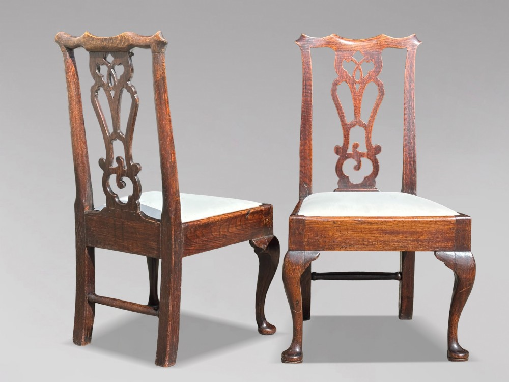 A pair of 18th-century George III oak Chippendale side chairs featuring carved pierced splats, upholstered drop-in seats, and cabriole front legs. View II