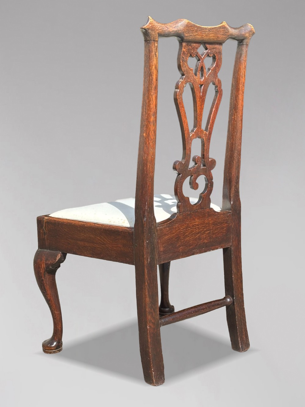 A pair of 18th-century George III oak Chippendale side chairs featuring carved pierced splats, upholstered drop-in seats, and cabriole front legs. View IV