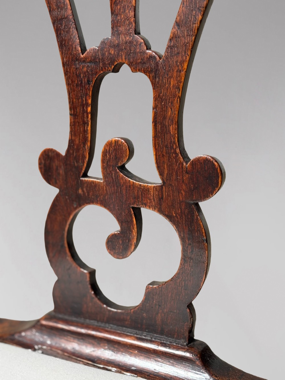 A pair of 18th-century George III oak Chippendale side chairs featuring carved pierced splats, upholstered drop-in seats, and cabriole front legs. View VI