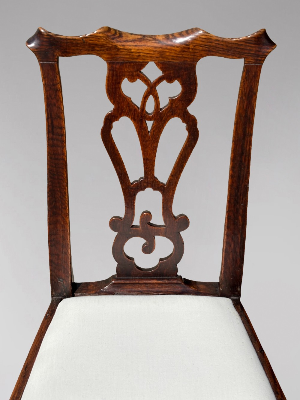 A pair of 18th-century George III oak Chippendale side chairs featuring carved pierced splats, upholstered drop-in seats, and cabriole front legs. View VIII