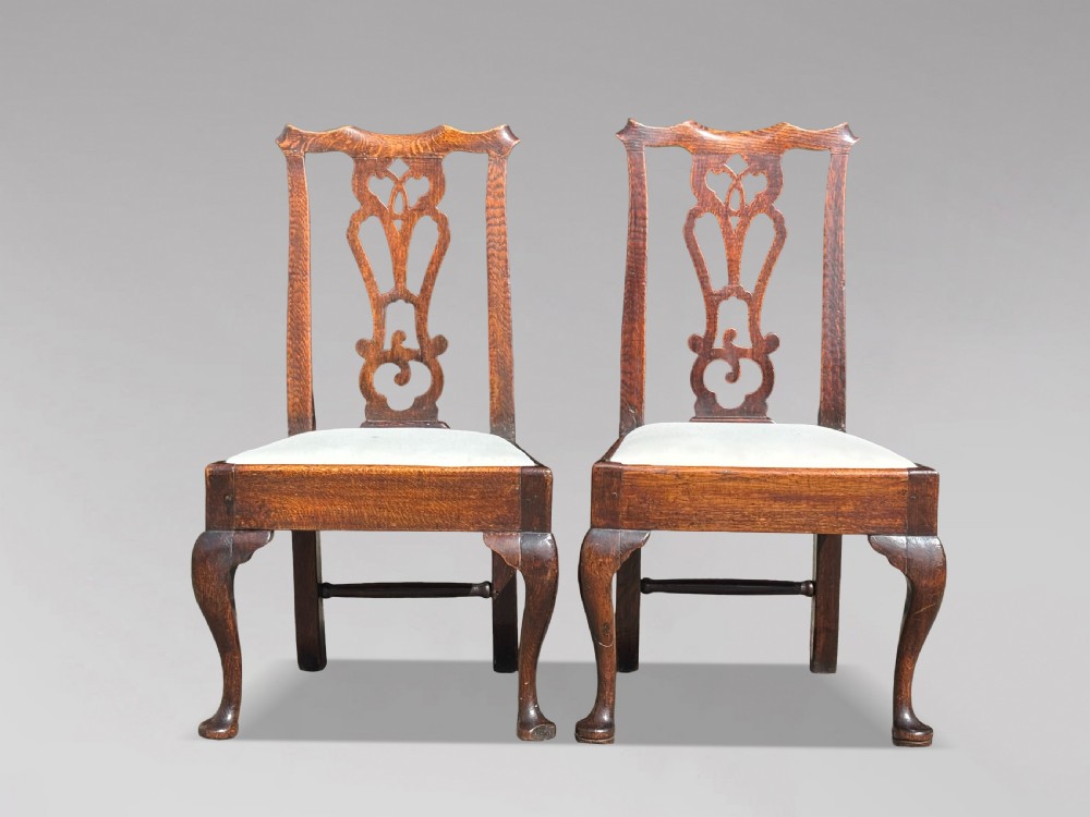A pair of 18th-century George III oak Chippendale side chairs featuring carved pierced splats, upholstered drop-in seats, and cabriole front legs. View IX