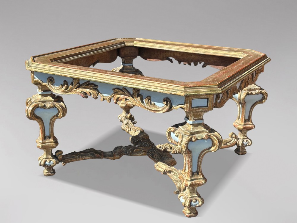 A square Italian Baroque style coffee table featuring a glass top, pale blue paint finish, carved gilt scrollwork frieze, ornate scrolled legs, and an X-shaped stretcher. View II