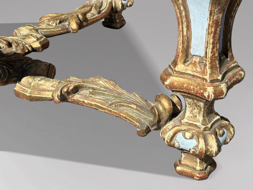 A square Italian Baroque style coffee table featuring a glass top, pale blue paint finish, carved gilt scrollwork frieze, ornate scrolled legs, and an X-shaped stretcher. View III