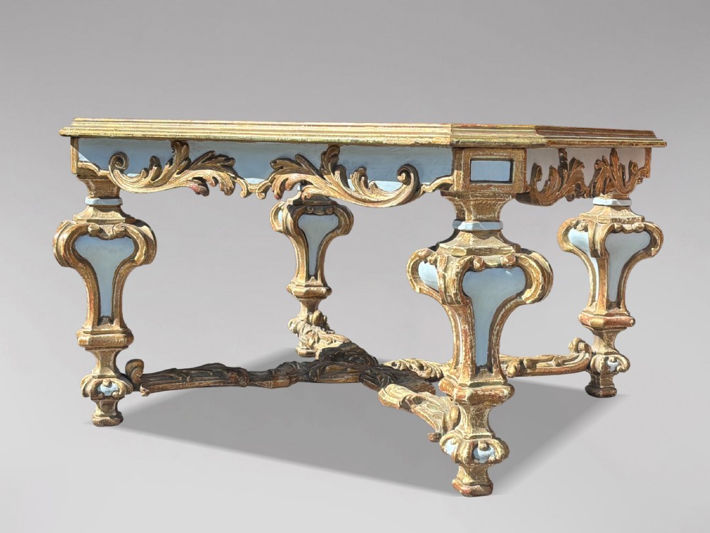 A square Italian Baroque style coffee table featuring a glass top, pale blue paint finish, carved gilt scrollwork frieze, ornate scrolled legs, and an X-shaped stretcher. View V