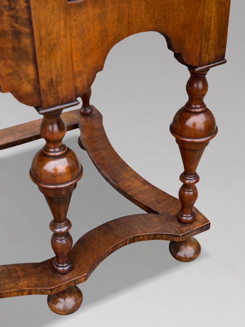 An 18th-century Queen Anne walnut chest on stand featuring figured veneers, brass drop handles, a shaped lower apron, and turned legs joined by stretchers. View IV