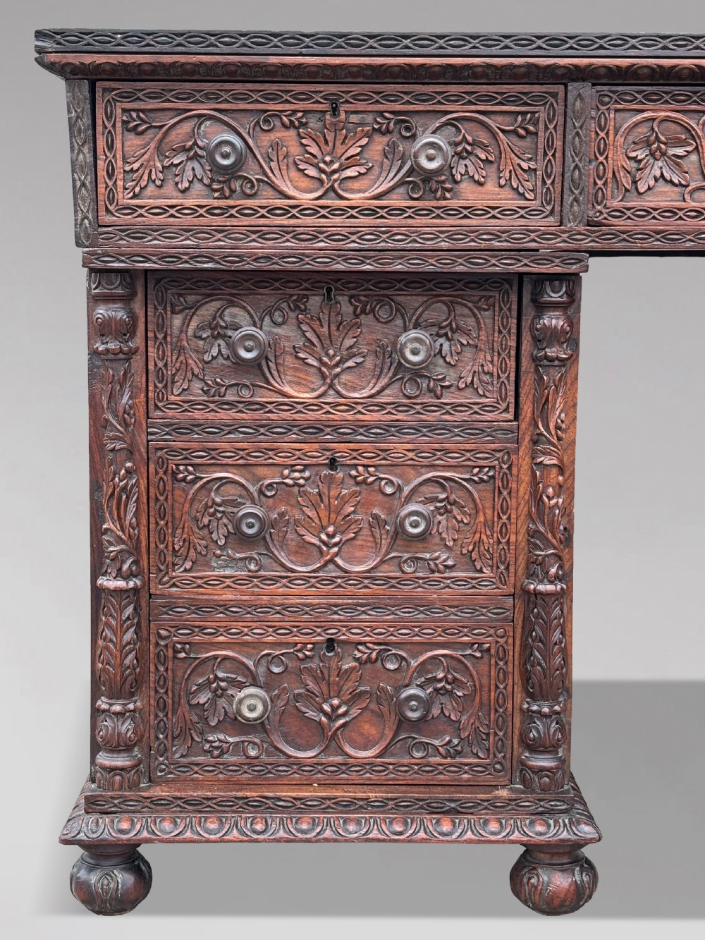 Nineteenth-century Anglo-Indian carved padauk partners desk featuring intricate foliate relief carvings across the pedestal drawers and side panels on turned bun feet. View IV