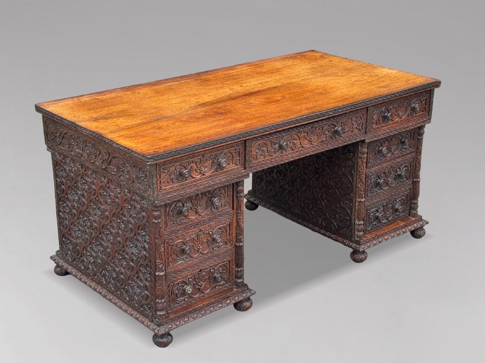 Nineteenth-century Anglo-Indian carved padauk partners desk featuring intricate foliate relief carvings across the pedestal drawers and side panels on turned bun feet. View XII