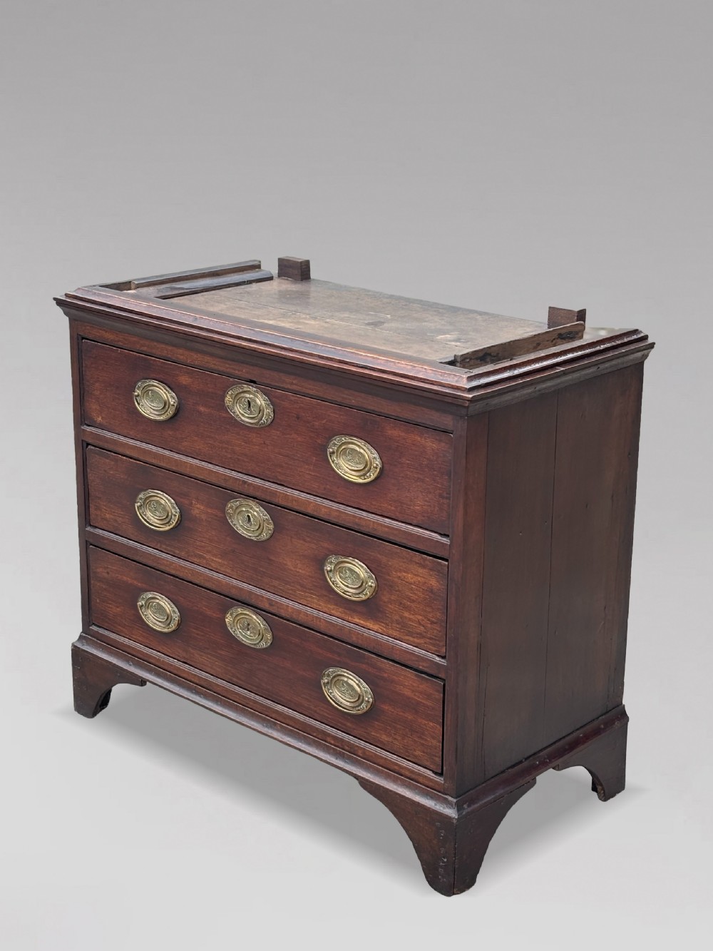 An 18th-century George III dark oak housekeepers cupboard featuring a fretwork gallery with a central turned finial, two upper panel doors, and three lower drawers with brass oval handles. View VII