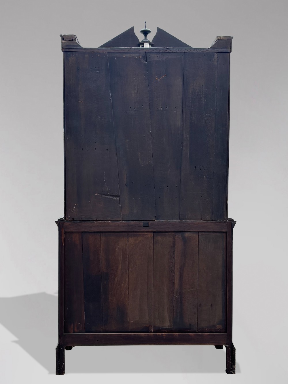 An 18th-century George III dark oak housekeepers cupboard featuring a fretwork gallery with a central turned finial, two upper panel doors, and three lower drawers with brass oval handles. View VIII