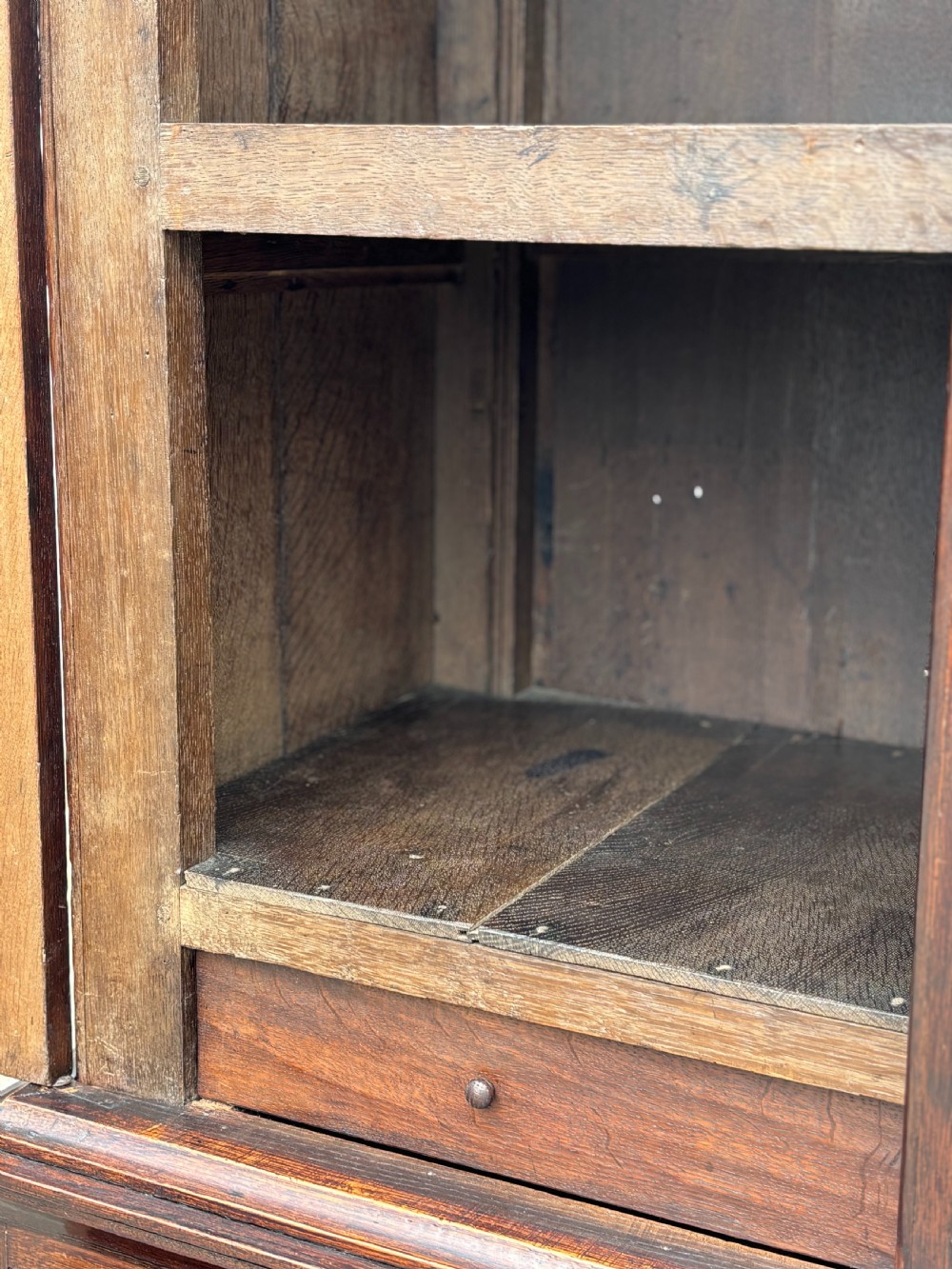 An 18th-century George III dark oak housekeepers cupboard featuring a fretwork gallery with a central turned finial, two upper panel doors, and three lower drawers with brass oval handles. View XI