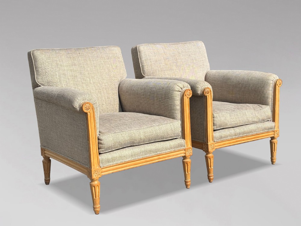 A pair of 19th-century French Louis XVI style armchairs featuring carved wooden frames, fluted legs, and neutral grey woven upholstery. View X